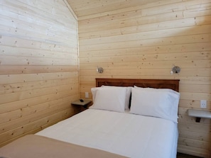 A wooden-paneled room with a bed, nightstand, and wall-mounted light fixture. - Brand-New Luxury Tiny Home Retreat with Loft & Stargazing Deck in Williams, Arizona (Williams)