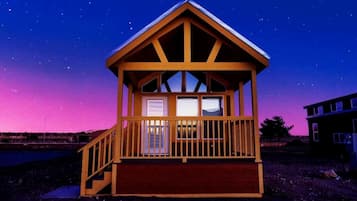 A wooden cabin with a balcony, windows, and a porch.