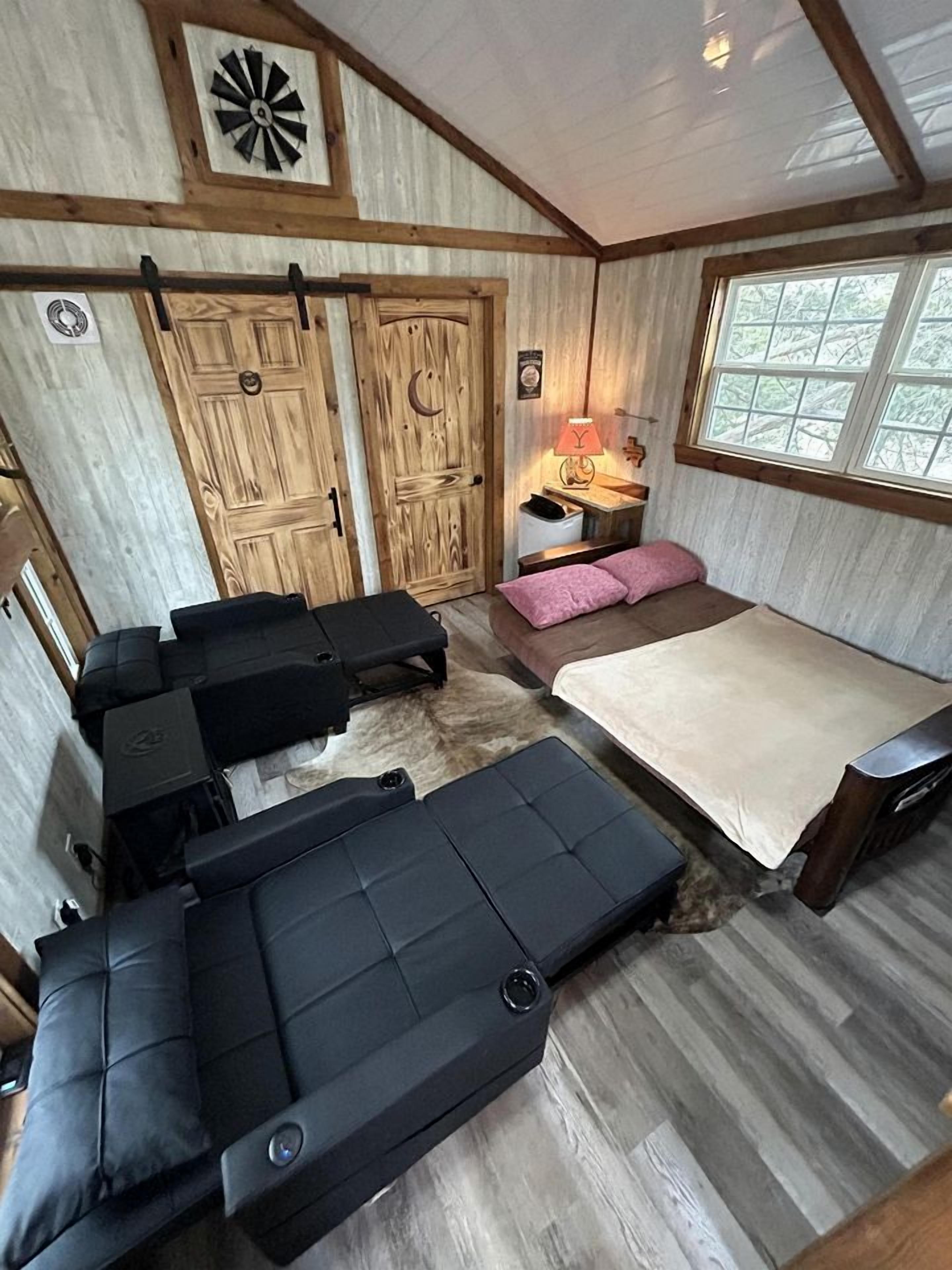 L’intérieur d’une cabine comprenant un lit, deux canapés, une petite table et une fenêtre.