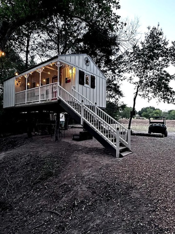 A cabin with a staircase leading to a deck, surrounded by trees.
