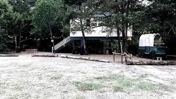 Une cabane rustique dotée d’un porche abrité, d’un escalier et d’un chariot couvert.