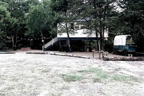 A rustic cabin with a covered porch, a staircase, and a covered wagon.