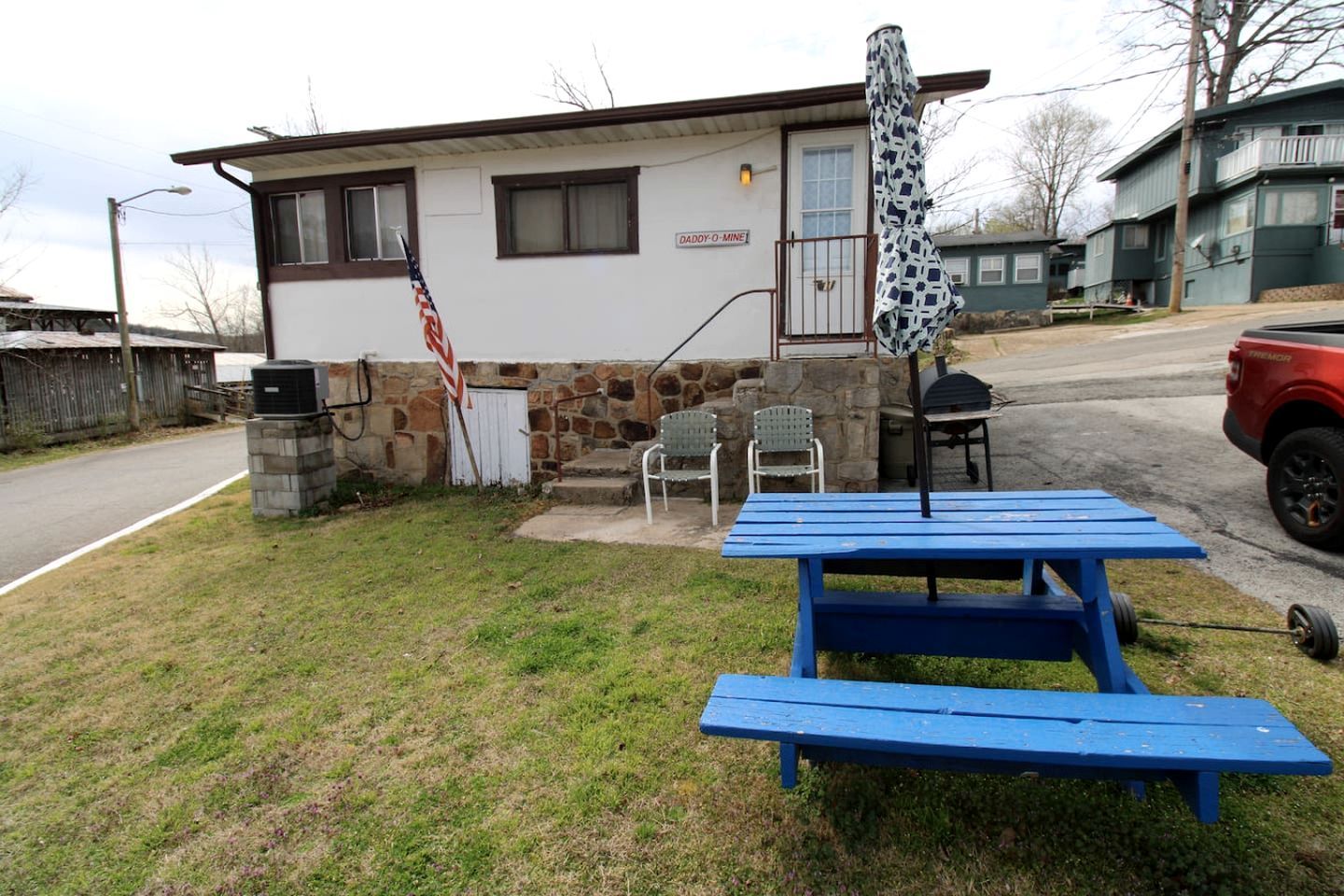 A small house with a stone exterior, a blue picnic table, and an American flag.
