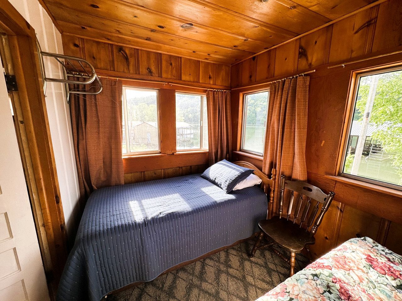 A small cabin-style room with a single bed, a chair, and a window.