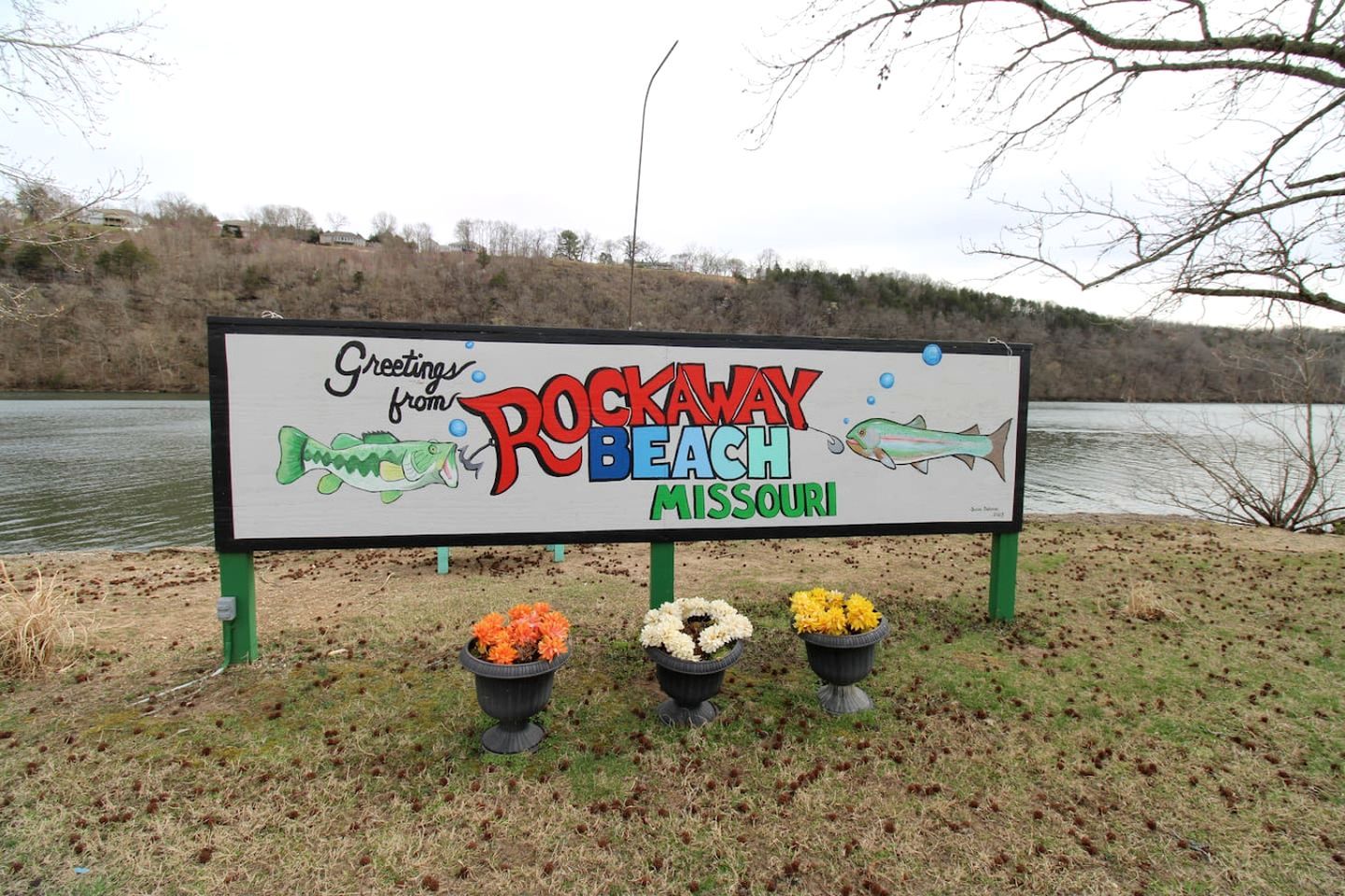 Un letrero con el texto 'Greetings from Rockaway Beach, Missouri' y una ilustración de un pez.