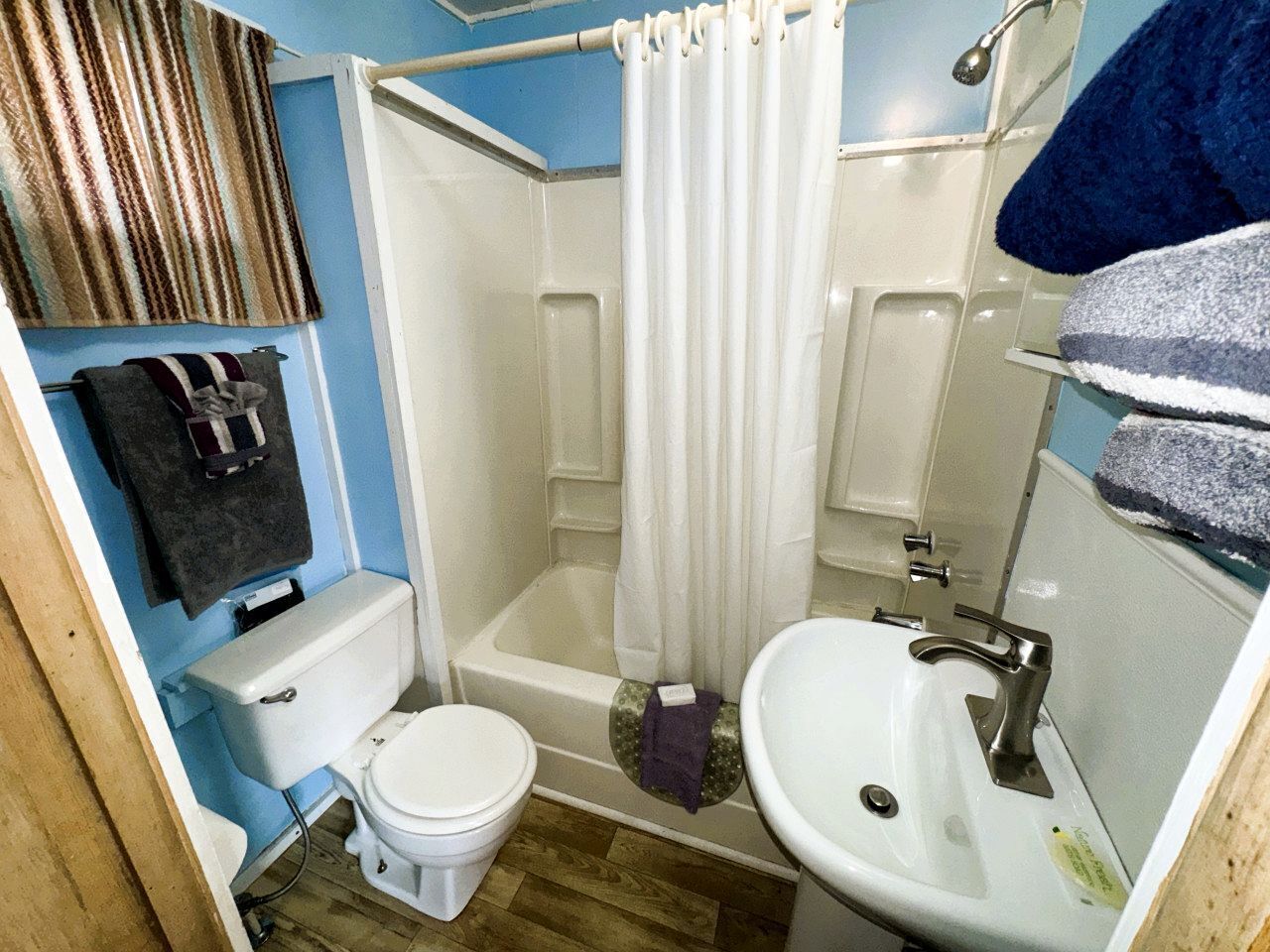 A bathroom with a toilet, shower, and sink.
