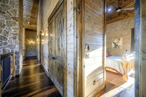 Un intérieur en bois avec un mur en pierre, un lit doté d’une tête de lit et un ventilateur de plafond.