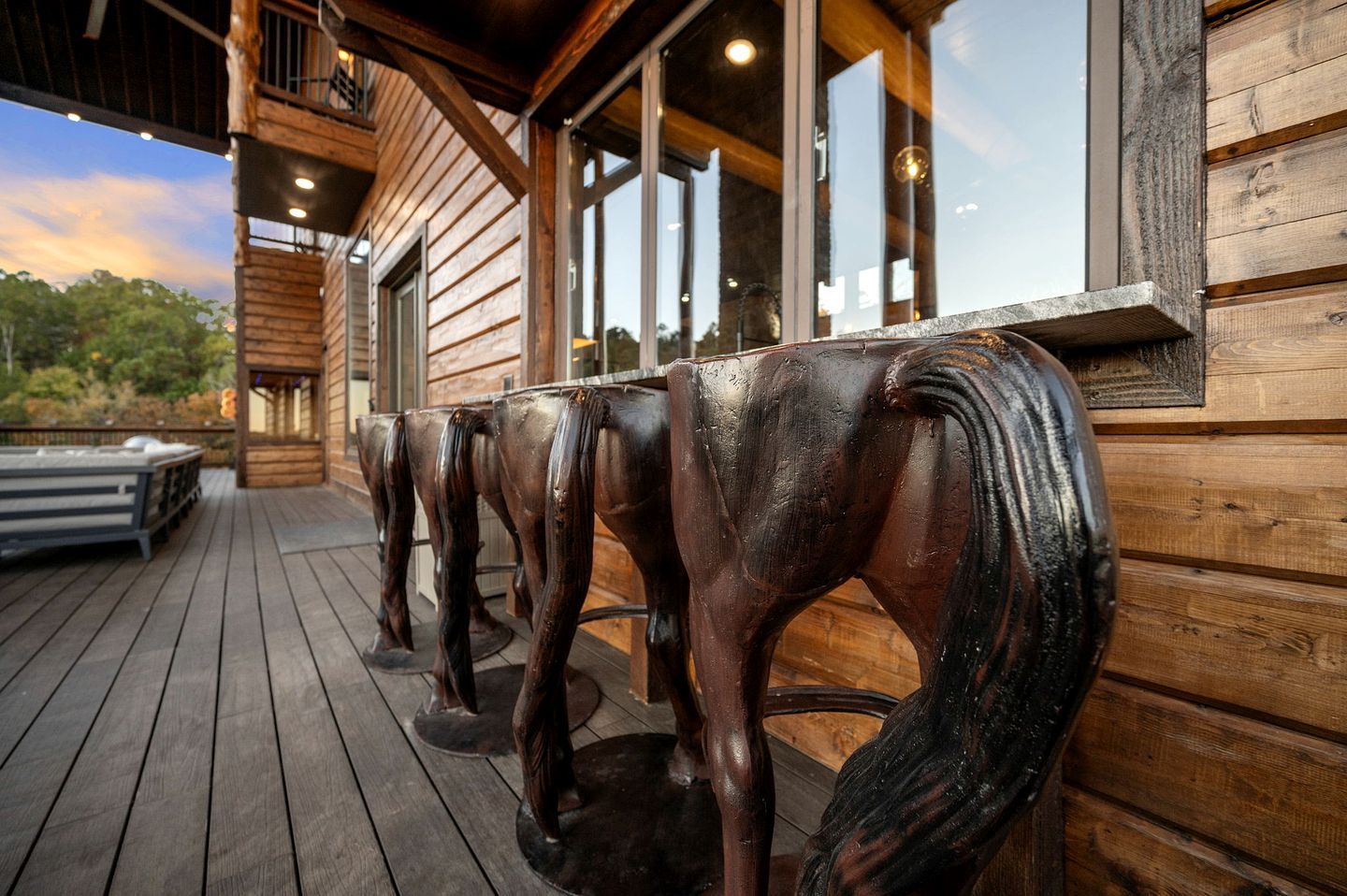 Une terrasse en bois ornée de statues de chevaux, un espace abrité avec des fenêtres et une façade de bâtiment en bois.