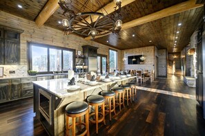 Une cuisine spacieuse dotée d’un grand îlot central, de tabourets de bar et d’une cheminée en pierre.