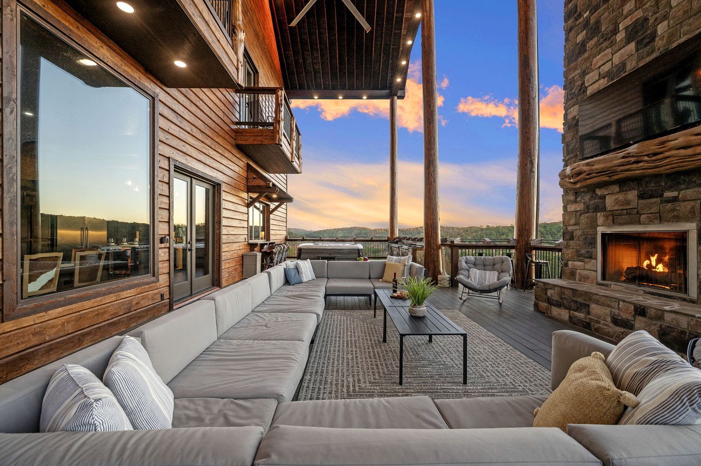 A covered outdoor seating area with a sofa, chairs, and a fireplace.