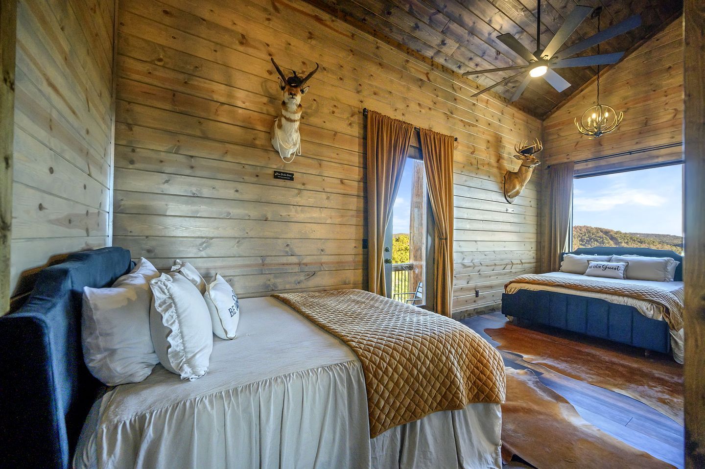 A wooden cabin bedroom with a bed, a sofa, and a view of the outdoors.