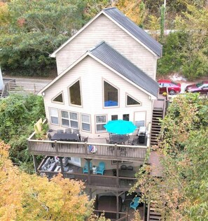 Ein zweistöckiges Haus mit Balkon, Terrasse und einer Sitzgelegenheit im Freien.
