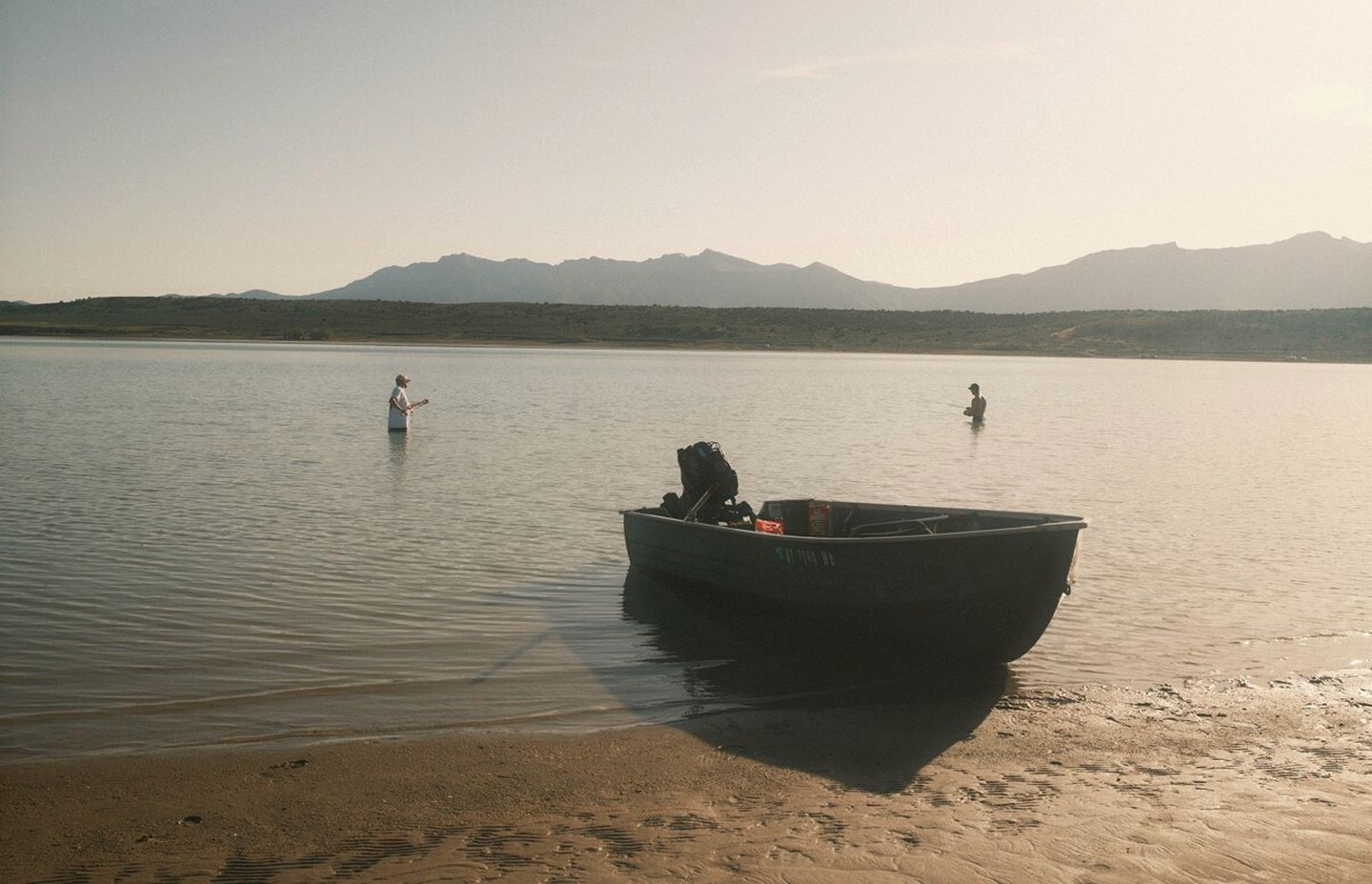 Un bateau sur une eau calme, avec des montagnes en arrière-plan.