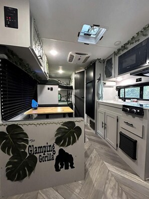 Una cocina compacta equipada con microondas, estufa y una pequeña mesa de comedor.