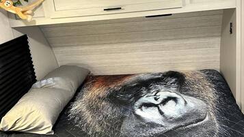 A bed with a quilted cover featuring a face design and the text 'ADVENTURE CREEK RANCH'.