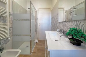 A bathroom with a glass shower enclosure, a white sink, a mirror, and a potted plant. - Near marina & promenade + free parking (Porto San Giorgio)