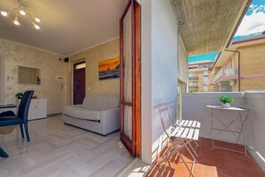 Un apartamento moderno con balcón, un sofá, una mesa de comedor y una mesita con una planta.