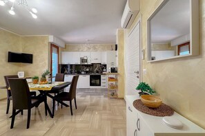 Una cocina moderna con armarios blancos, microondas y un comedor con mesa y sillas.