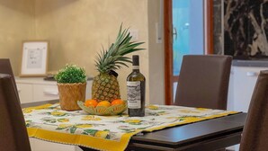 Uma mesa de jantar com uma cesta de frutas, uma garrafa e uma pequena planta.