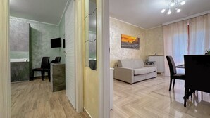 Uma sala de estar moderna com um sofá, uma mesa de jantar e uma TV fixada na parede.