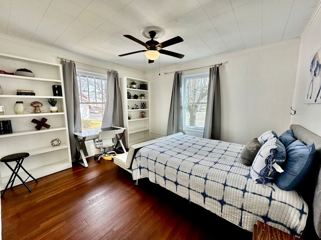 A bedroom with a bed, a desk, and shelves.