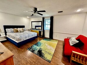 A bedroom with a bed, a desk, a red sofa, and a ceiling fan. - Spacious Vacation Home Near Trails & Entertainment in Hot Springs, Arkansas (Hot Springs)