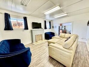 Una sala de estar con chimenea, televisor, sofá y un sillón azul.