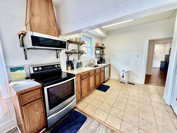 Una cocina con estufa, microondas, gabinetes de madera y una ventana.