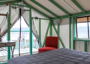 Une pièce aménagée comme une tente, avec un lit, une chaise rouge et une table.