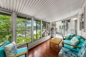 A sunroom with large windows, a wooden bench, and teal upholstered furniture. - Enormous Cabin Fully Loaded Dock for Water Sports in Tennessee (Rocky Top)