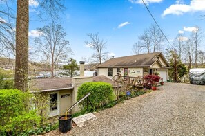 A single-story house with a front porch, a garage, and a gravel driveway. - Enormous Cabin Fully Loaded Dock for Water Sports in Tennessee (Rocky Top)