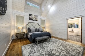A bedroom with a bed, bedside tables, a large rug, a headboard, and a window with blinds. - Secluded Luxury Cabin for Couples with Soaker Tub & Forest Views in Oklahoma (Broken Bow)