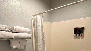 Ein Badezimmer mit Toilette, einer Duschkabine, einem Handtuchhalter und einem Mülleimer.