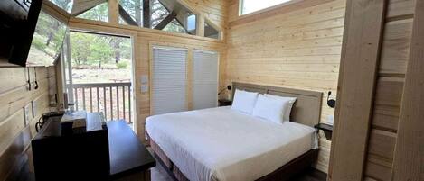 Ein Schlafzimmer einer Holzhütte mit einem Bett, einem Schreibtisch und einem Fernseher.