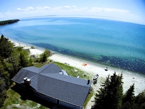A coastal property with a large house, a beach, and a view of the sea.