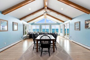 A dining area with a table and chairs, large windows, and a view of the ocean.