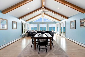A dining area with a table and chairs, large windows, and a view of the ocean.