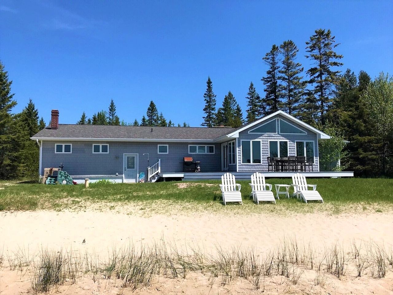 A two-story house with a covered porch and beach chairs.