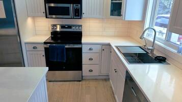 A compact kitchen with white cabinetry, a microwave, an oven, and a sink.