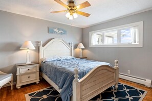 A bedroom with a bed, nightstands, a ceiling fan, a window, and a rug.