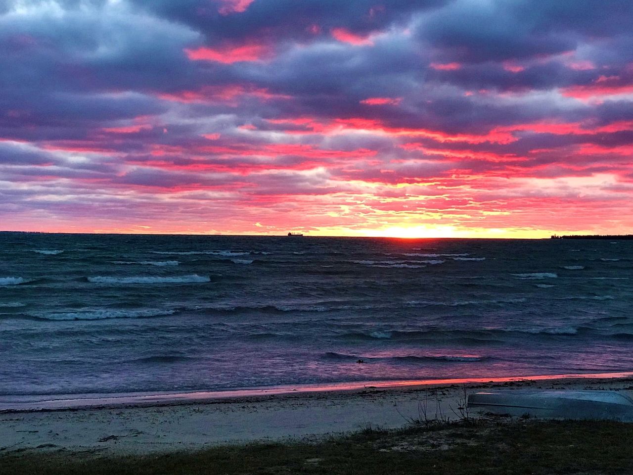 A beach with waves and a sunset.