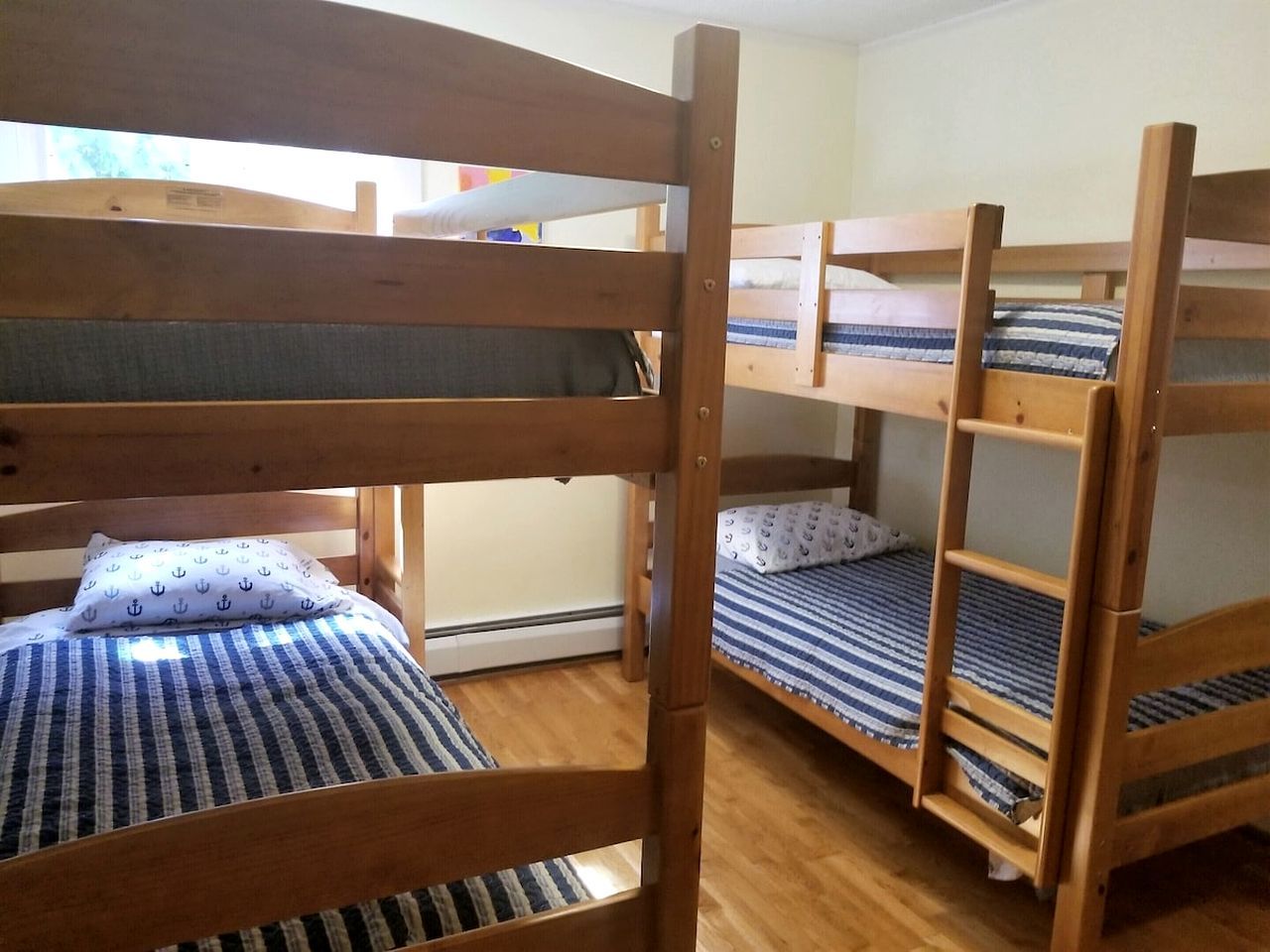 Bunk beds with striped bedding, wooden frames, and a window providing natural light.