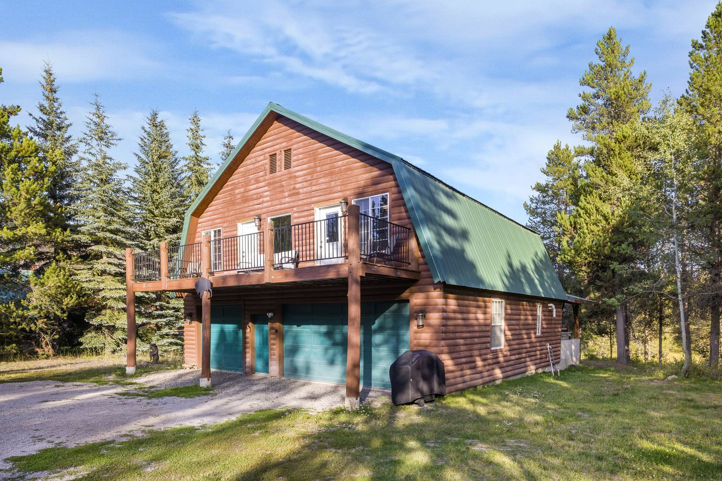 A log cabin with a balcony, a garage, and a covered porch.
