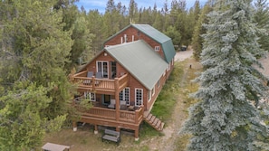 Une cabane en rondins dotée d’un balcon, entourée d’arbres.
