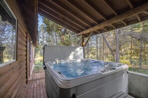 Ein Whirlpool in einer Holzhütte mit Blick auf einen Wald.