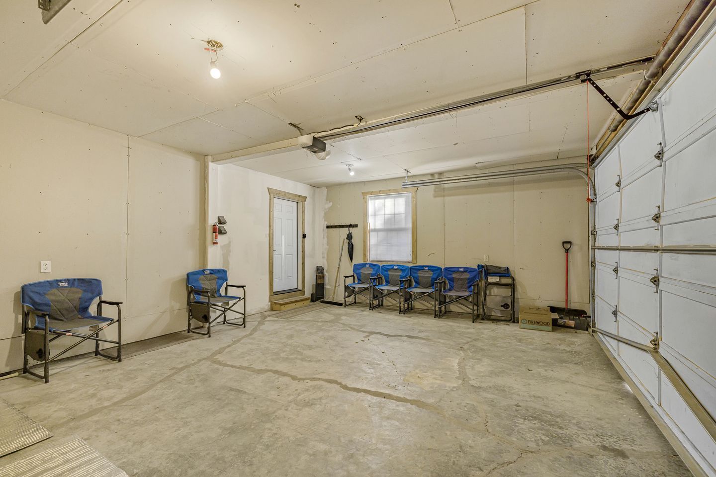 A spacious room with a concrete floor, a door, and a row of blue chairs.