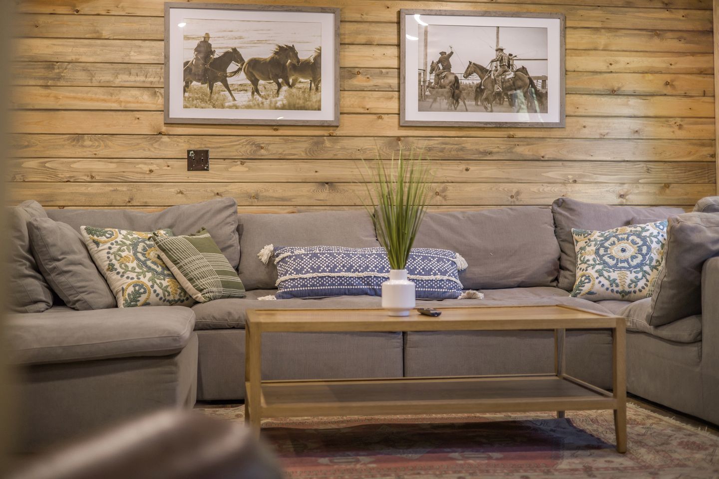 A living room with a grey sofa, a wooden coffee table, and two framed pictures on the wall.