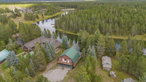 Ein Luftbild zeigt eine Hütte mit mehreren Gebäuden, einem See und dichtem Wald.