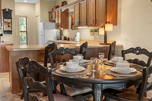 A dining area with a round table set for four, surrounded by dark wooden chairs with intricate designs. - Caddy Corner Condo  Cozy Stay (Branson)