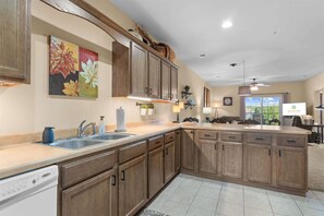 A kitchen with wooden cabinets, a dishwasher, and a large island with a sink. - Caddy Corner Condo  Cozy Stay (Branson)